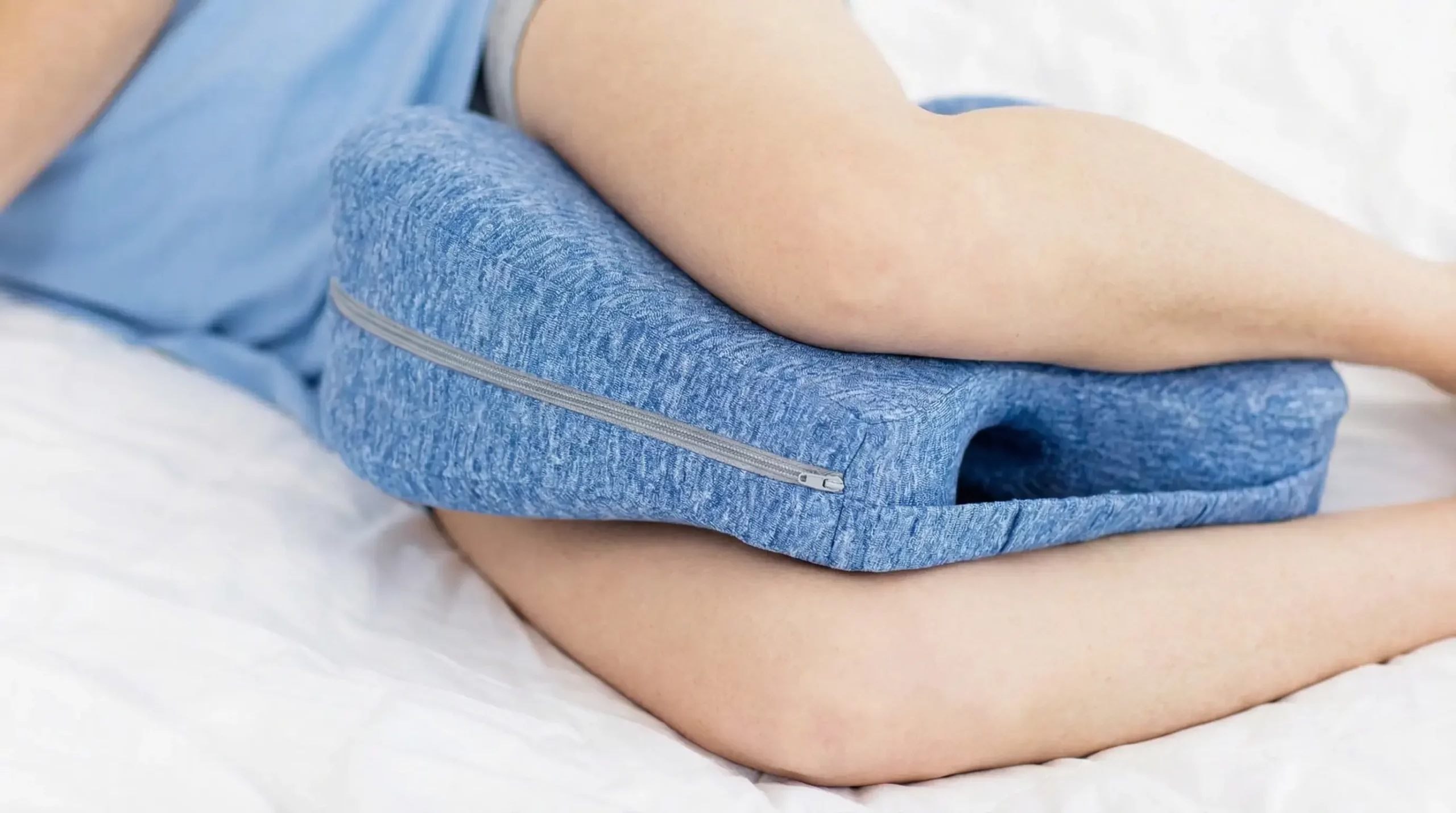 The Sciatica Pillow positioned between a sleeper's knees